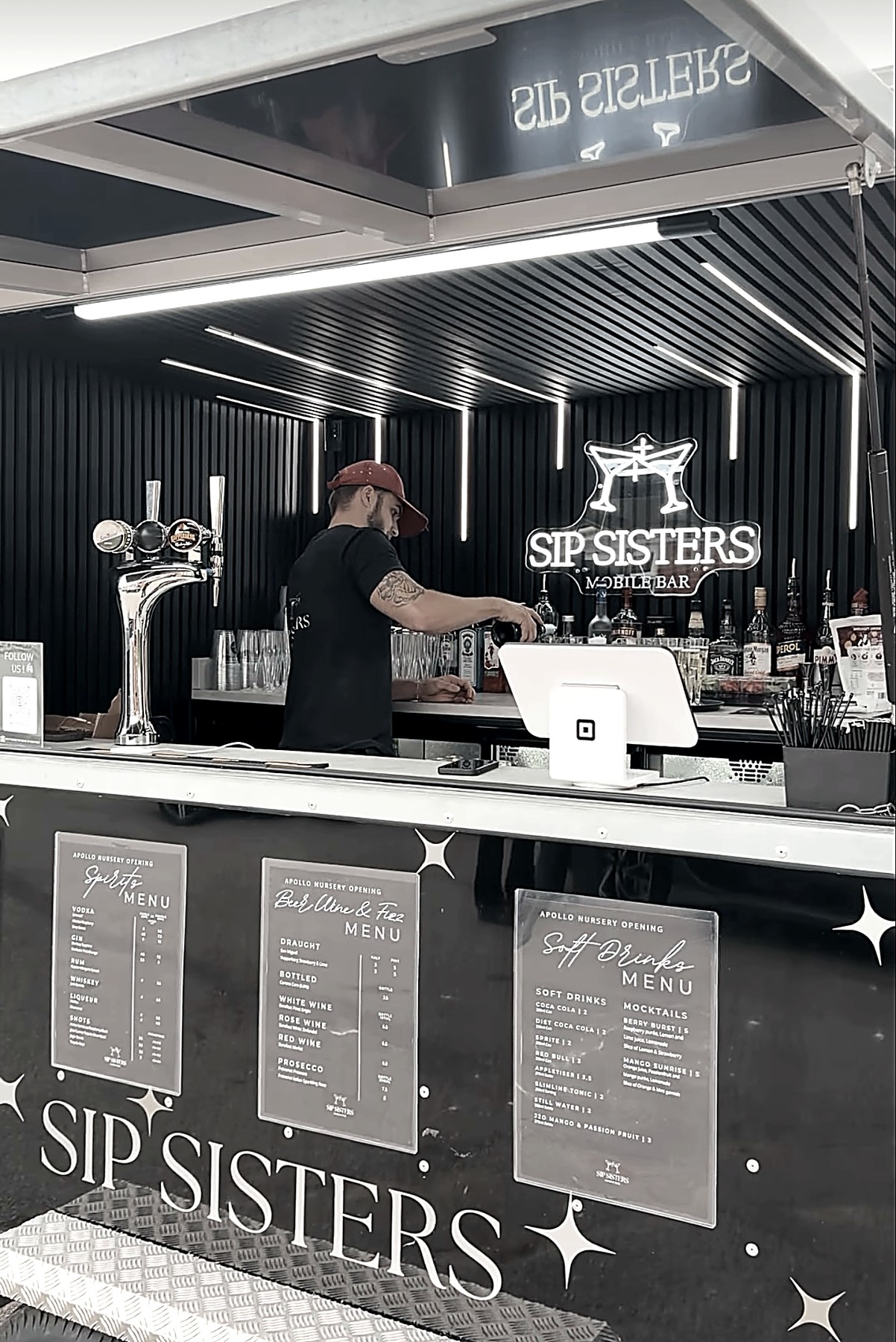 Inside the Sip Sisters bar trailer with illuminated signage and draught taps